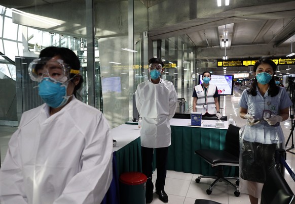epa08158481 Thai health official wearing protective masks monitor passengers from international flights arriving at Suvarnabhumi Airport, Samut Prakan province, Thailand, 24 January 2020. Thai health  ...