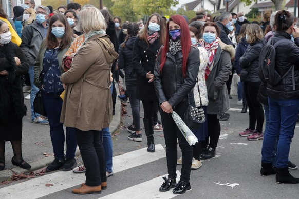 Residents gather outside the school where a slain history teacher was working, Saturday, Oct. 17, 2020 in Conflans-Sainte-Honorine, northwest of Paris. French President Emmanuel Macron denounced what  ...