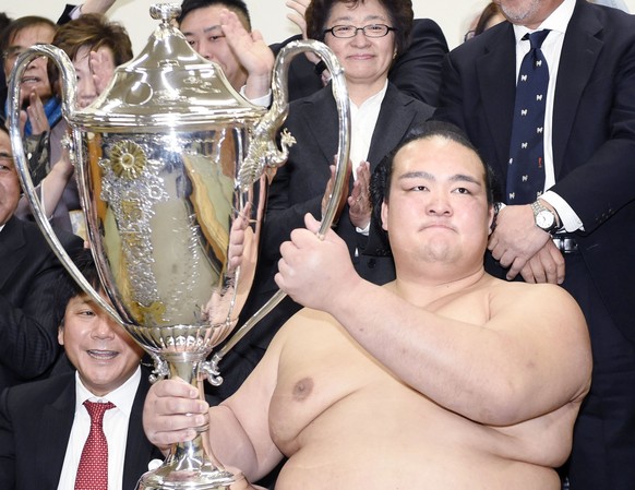 Ozeki Kisenosato, accompanied by his father Sadahiko Hagiwara, right, and mother Yumiko, holds the trophy after defeating Mongolian grand champion Hakuho during the final day bout of the New Year Gran ...