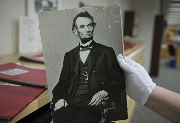 In this Monday, April 6, 2015 photo, Karen Needles holds up a photograph of President Abraham Lincoln at the National Archives in College Park, Md. Three blocks away, 150 years earlier, Lincoln was fe ...