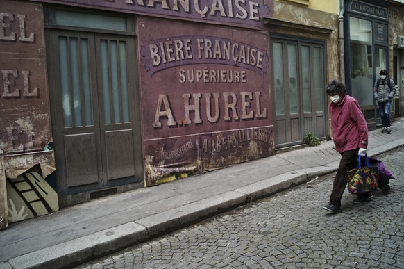 A woman wearing a face mask walks in a deserted street transformed in s movie set during nationwide confinement measures to counter the Covid-19, in Paris, Thursday, April 30, 2020. France continues t ...