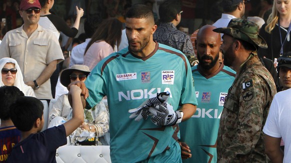 England soccer star David James, center, touches fists with a young boy while he along with French player Nicolas Anelka, second right, arrive to play an exhibition soccer match in Lahore, Pakistan, S ...