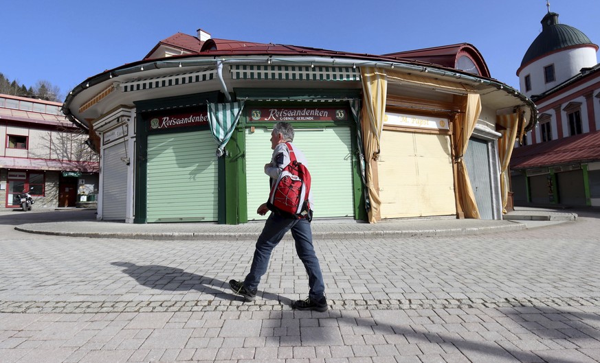 A man walks past a closed shop of a pilgrim market in Mariazell, Austria, Tuesday, Feb. 23, 2021. The Austrian government has moved to restrict freedom of movement for people, in an effort to slow the ...