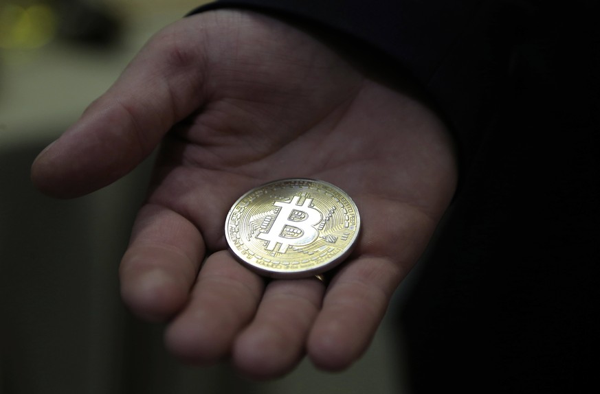 epa06170774 A visitor holds a Bitcoin (virtual currency) souvenir coin, during a webinar by Russian businessman, Orthodox activist and founder the Crypto exchange CryptoSterlingClub Alisa, German Ster ...