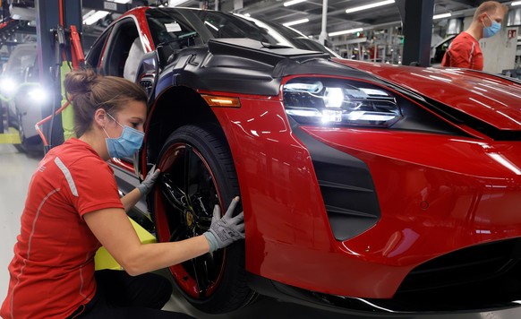 epa08416389 Workers wearing protective face masks and gloves work in the production of the &#039;Taycan&#039; electric sports cars at an assembly line of German car manufacturer Porsche in Stuttgart,  ...