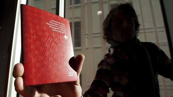 Un homme tient un passeport biometrique Suisse dans le nouveau centre de biometrie au Flon ce vendredi 21 janvier 2011 a Lausanne. Ce centre va recolter les donnees biometriques pour les passeports su ...