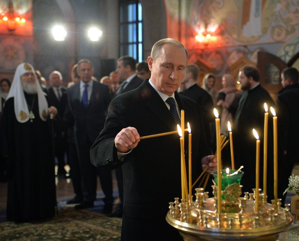 epa04520324 Russian President Vladimir Putin lights a candle in St. Sergiy of Radonezh church in Tsarskoye Selo outside St. Petersburg, Russia, 08 December 2014. EPA/ALEXEY DRUGINYN / RIA NOVOSTI / KR ...