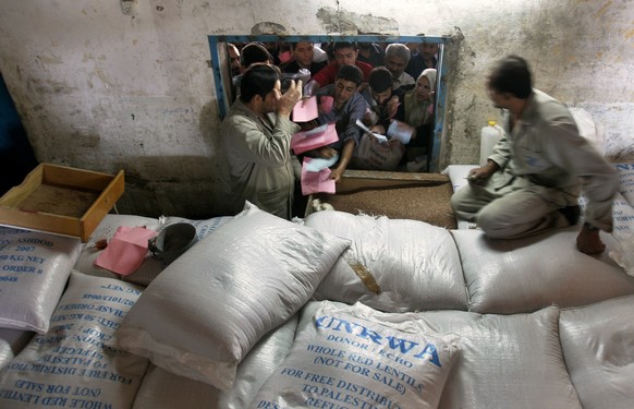 FILE - In this May 8, 2008 file photo, U.N. employees distribute food to Palestinians at the U.N. Relief and Works Agency, (UNRWA), warehouse in the Shati refugee camp, in Gaza City. The United Nation ...