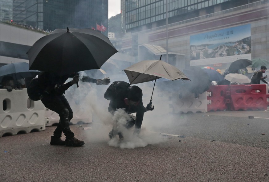 A protestor picks up an exploded tear gas shell to throw back to policemen in central Hong Kong, Saturday, Aug. 31, 2019. The mostly young, black-shirted protesters took over roads and major intersect ...