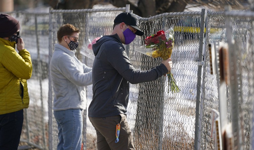 Kiefer Johnson places a bouquet of flowers into a makeshift fence put up around the parking lot outside a King Soopers grocery store where a mass shooting took place a day earlier, in Boulder, Colo.,  ...