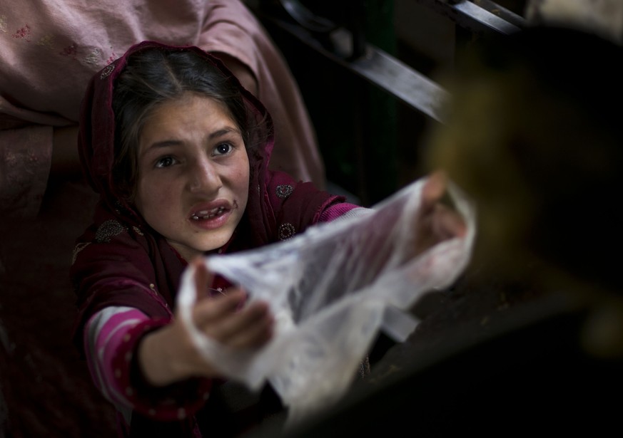 A Pakistani poor girl extends her plastic bag to receive free food for her family, distributed at local shrine in suburbs of Islamabad, Pakistan, Friday, Nov. 20, 2015. Pakistan also observed Universa ...