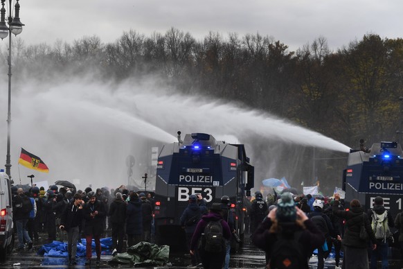 epa08827234 Riot police use water cannons to break up a demonstration against German coronavirus restrictions, near the Brandenburg Gate in Berlin, Germany, 18 November 2020. While German interior min ...