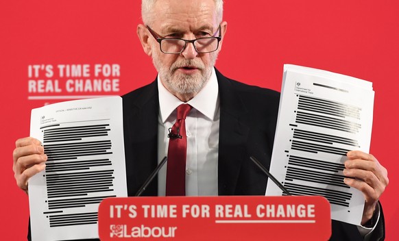 epa08028462 Labour Party Leader Jeremy Corbyn holds up redacted documents of secret talks between the UK and US governments during a speech on the NHS in London, Britain, 27 November 2019. Britons go  ...
