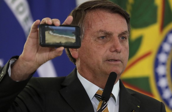 Brazil&#039;s President Jair Bolsonaro shows a photo of a beach during a ceremony presenting a program to restart tourism, amid the COVID-19 pandemic, at Planalto Palace in Brasilia, Brazil, Tuesday,  ...