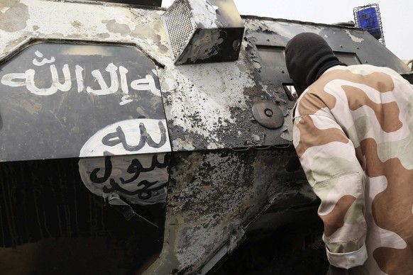 Panzerfahrzeug mit aufgepinselter Dschihadfahne: Ein tschadischer Soldat begutachtet zerstörtes Boko-Haram-Kriegsgerät.