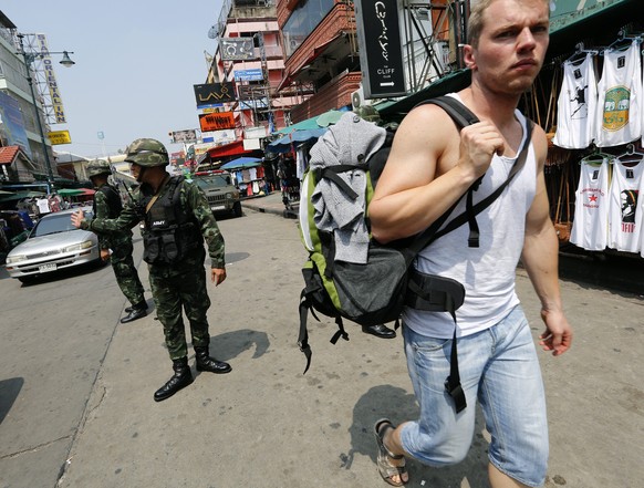 epa04447518 Foreign tourist walks past Thai soldiers as they inspect shops as they take action to clean up sidewalk stalls and bring order to the tourist popular area of Khao San road in Bangkok, Thai ...