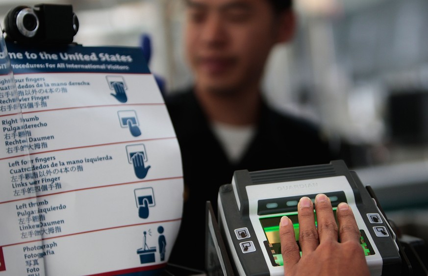NEWARK, NJ - AUGUST 24: A traveler arriving from overseas is fingerprinted while his paperwork is checked by a border patrol official at the passport control line in Newark International Airport Augus ...