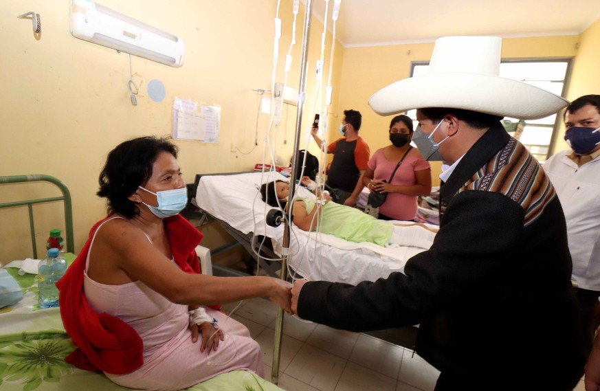 epa09380870 A handout photo made available by the Presidency of Peru shows President of Peru Pedro Castillo (2-R) visiting a person who was injured in an earthquake in Piura, a region located about 99 ...
