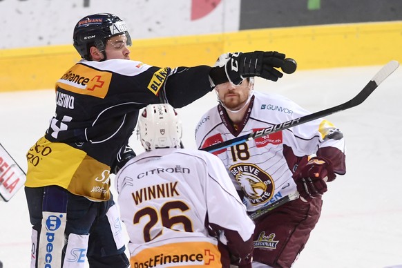 Ambri&#039;s player Nick Plastino, Servette&#039;s player Daniel Winnik, Servette&#039;s player Jeremy Wick, from left, fights for the puck, during the preliminary round game of National League Swiss  ...