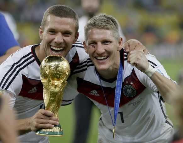 FILE - In his July 13, 2014 file picture Germany&#039;s Bastian Schweinsteiger and Lukas Podolski, left, celebrate with the World Cup trophy following their 1-0 victory over Argentina after the World  ...