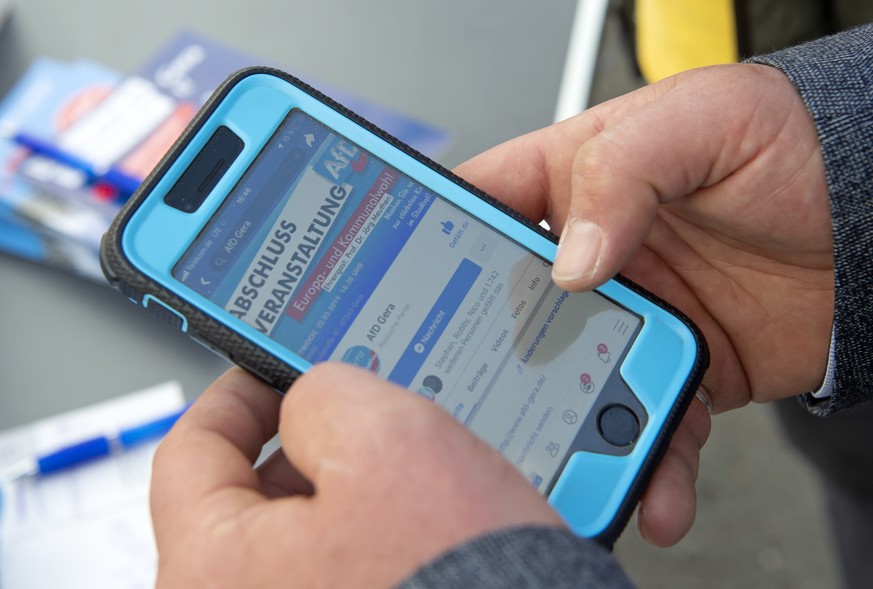 In this Friday, May 17, 2019 photo a man looks to an AfD website of the district Gera on his mobilphone during the street Europe and communal election campaigning of the far-right Alternative for Germ ...