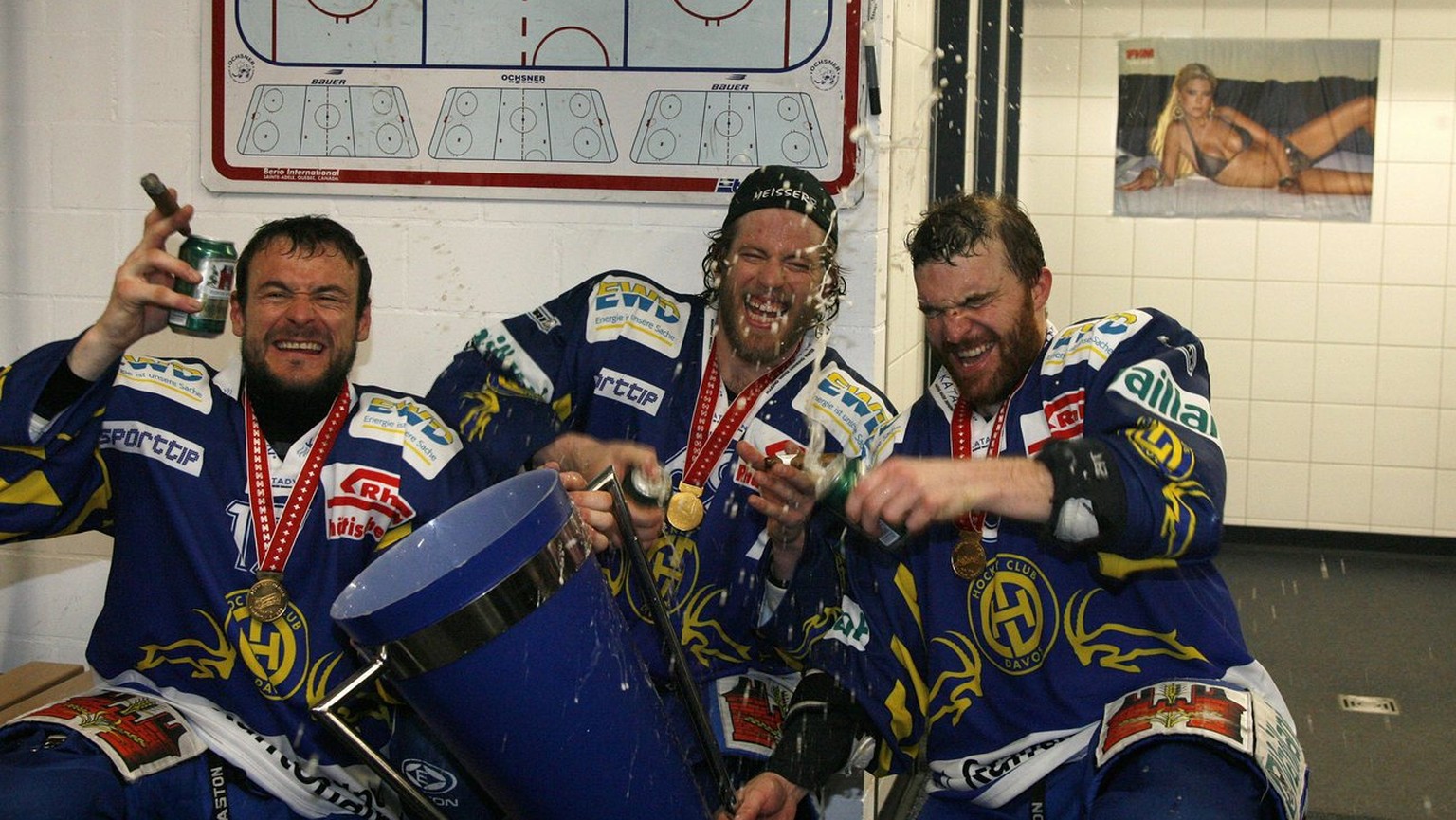 Die Davoser Gian Marco Crameri, Sandro Rizzi und Captain Marc Gianola, von links nach rechts, feiern in der Kabine mit dem Pokal den Schweizermeistertitel im siebten Playoff Eishockey Meisterschaftssp ...