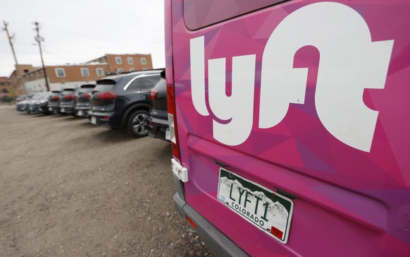 FILE - In this April 30, 2020, file photo, Kia Neros that are part of the Lyft ride-hailing fleet sit unused in a lot near Empower Field at Mile High in Denver. Lyft is still feeling the pandemic