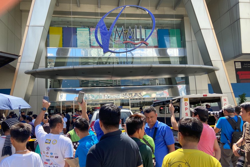 People gather outside the V-Mall where gunshots rang out inside, in Manila, Philippines, Monday, March 2, 2020. Philippine police surrounded the shopping mall after a gunman opened fire and took sever ...