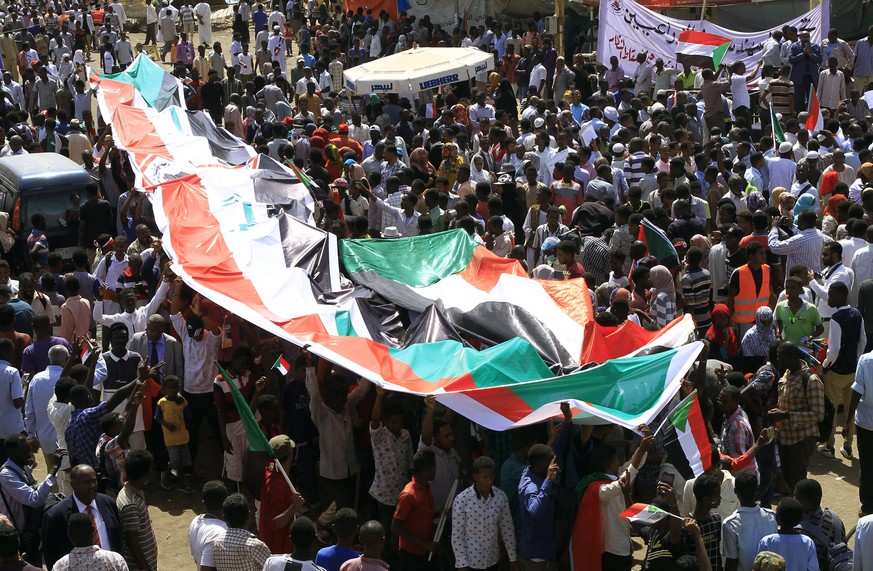 epa07527898 Sudanese protesters deploy their national flag as they protest outside the army headquarters in Khartoum, Sudan, 25 April 2019. Sudanese from other parts of the country joined the capital  ...