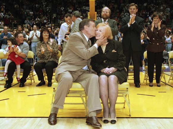 FILE - In this Jan. 19, 1998 file photo, Los Angeles Lakers announcer Chick Hearn kisses his wife Marge during a halftime ceremony honoring his 3,000th consecutive Lakers broadcast for the NBA basketb ...