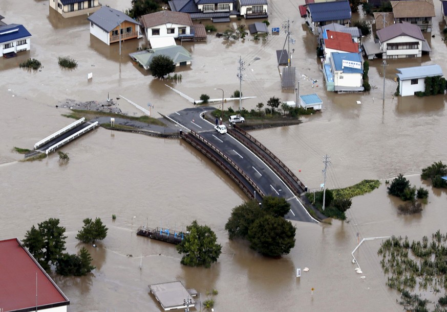 Cars are stranded on a road as the city is submerged in muddy waters after an embankment of the Chikuma River broke, in Nagano, central Japan, Sunday, Oct. 13, 2019. Rescue efforts for people stranded ...