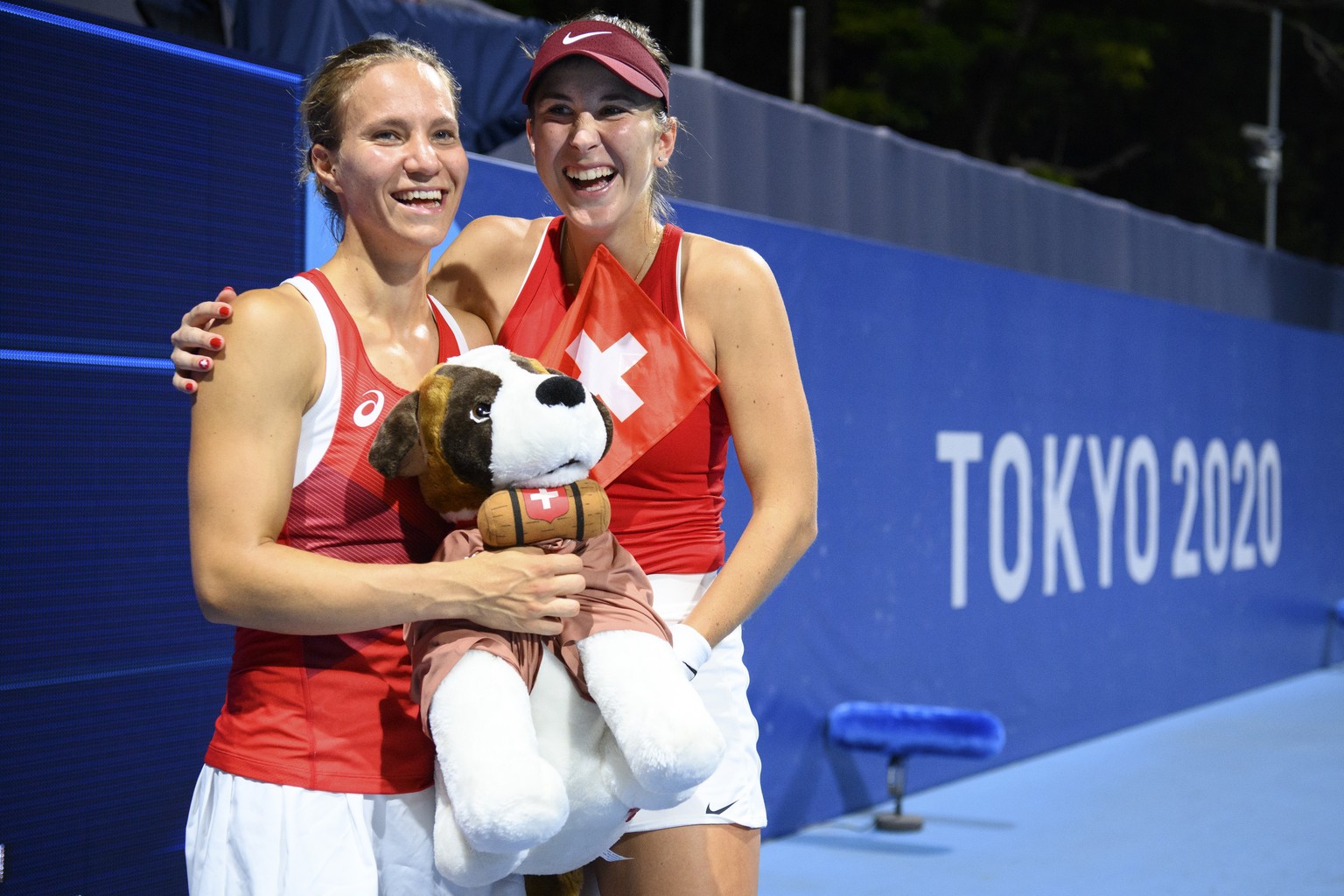 Belinda Bencic, right, and Viktorija Golubic, left, of Switzerland celebrate with the Swiss mascot dog Barry after winning against Laura Pigossi and Luisa Stefani of Brazil during the women&#039;s dou ...