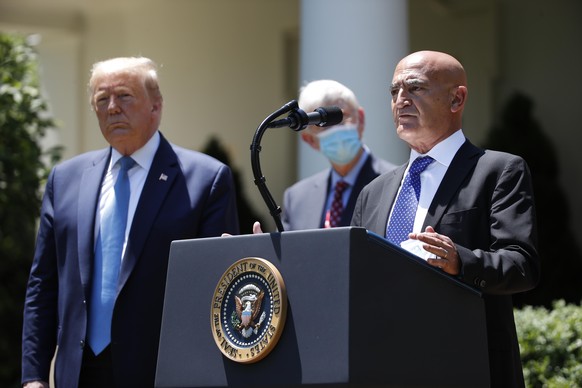 President Donald Trump, left, listens as Moncef Slaoui, a former GlaxoSmithKline executive, speaks about the coronavirus in the Rose Garden of the White House, Friday, May 15, 2020, in Washington. (AP ...