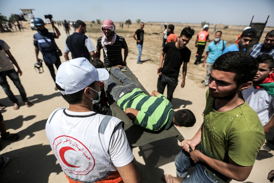 epa06793611 Palestinian protesters carry a wounded protester during the clashes after Friday protest near the border in the east of Khan Younis town southern Gaza Strip, 08 June 2018. Protesters call  ...