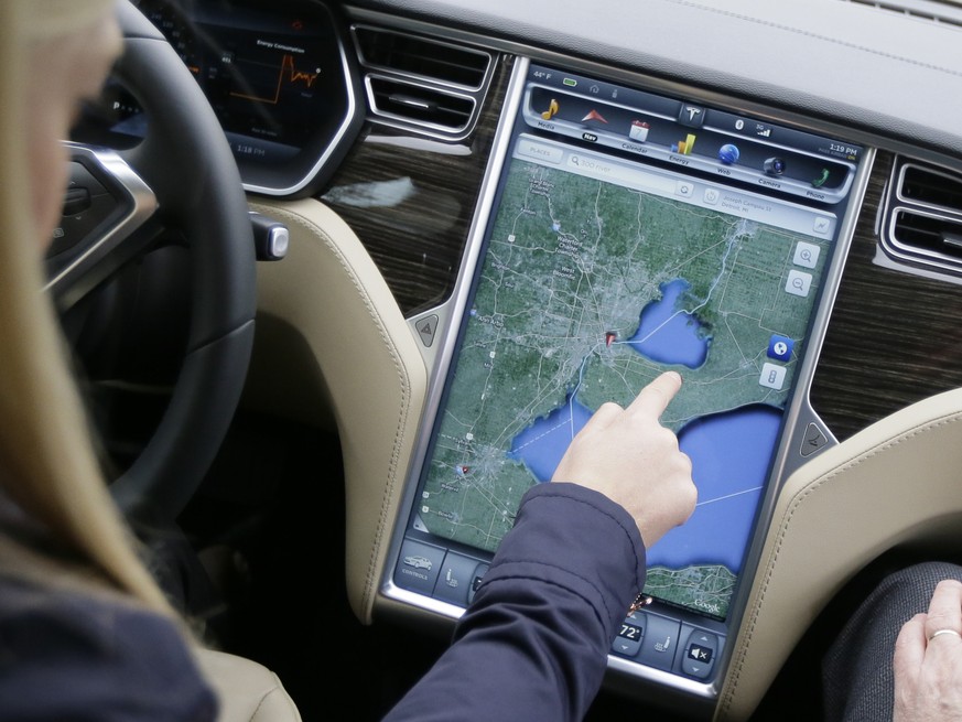 In a photo from Tuesday, April 7, 2015 in Detroit, Alexis Georgeson of Tesla Motors, shows off the navigation screen of the new Tesla Model S 70D during a test drive. Electric car maker Tesla Motors i ...