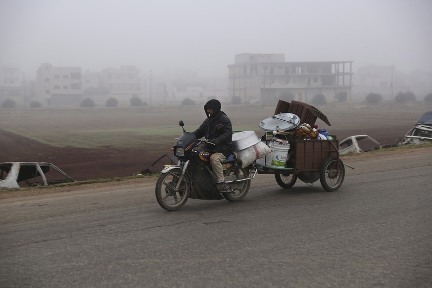 A man carries household goods on a motorbike while fleeing Maaret al-Numan, Syria, ahead of a government offensive, Monday, Dec. 23, 2019. (AP Photo/Ghaith al-Sayed)