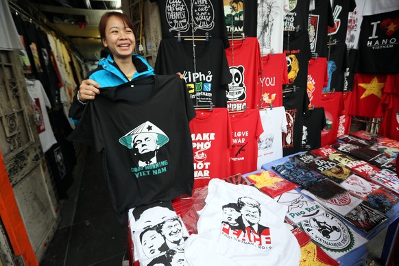 epa07386734 A girl holds a newly designed and printed t-shirt with the portraits of US President Donald Trump at a store in Hanoi, Vietnam, 22 February 2019. The second summit between US President Don ...