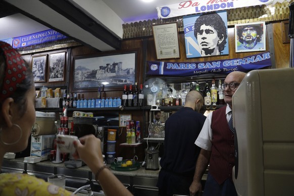 A woman drinks her espresso inside the Bar Nilo where a makeshift shrine of soccer legend and former Napoli player Diego Armando Maradona is displayed in downtown Naples, Italy, Wednesday, Sept. 18, 2 ...