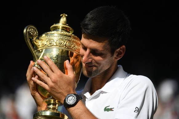 epa06890894 Novak Djokovic of Serbia with the championship trophy as he celebrates defeating Kevin Anderson of South Africa in the men&#039;s singles final of the Wimbledon Championships at the All En ...