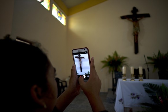 A parishioner makes a photo of the crucifix above the altar at the newly consecrated Sagrado Corazon de Jesus, or Sacred Heart, Catholic church, in Sandino, Cuba, Saturday, Jan. 26, 2019. Of the three ...