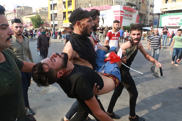 An injured protester is carried after reacting to tear gas fired by security forces during a protest in Tahrir Square, in central Baghdad, Iraq, Tuesday, Oct. 1, 2019. Iraq officials say 1 person has  ...