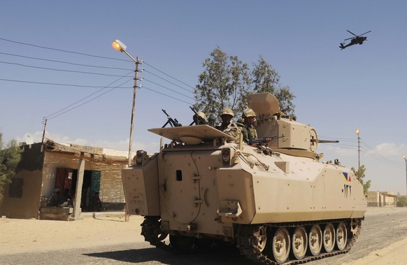 FILE - In this Tuesday, May 12, 2013 file photo, Egyptian Army soldiers patrol in an armored vehicle backed by a helicopter gunship during a sweep through villages in Sheikh Zuweyid, north Sinai, Egyp ...