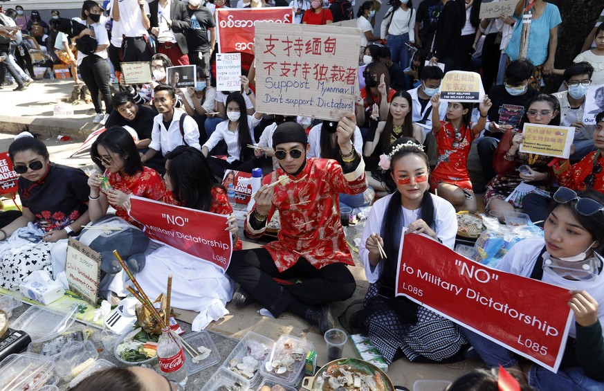 epa09004196 Myanmar model Paing Takhon (L) wearing a Chinese costume and his friend have seafood hotpot and barbecue as they hold placards during a protest against the military coup in front of the Ch ...