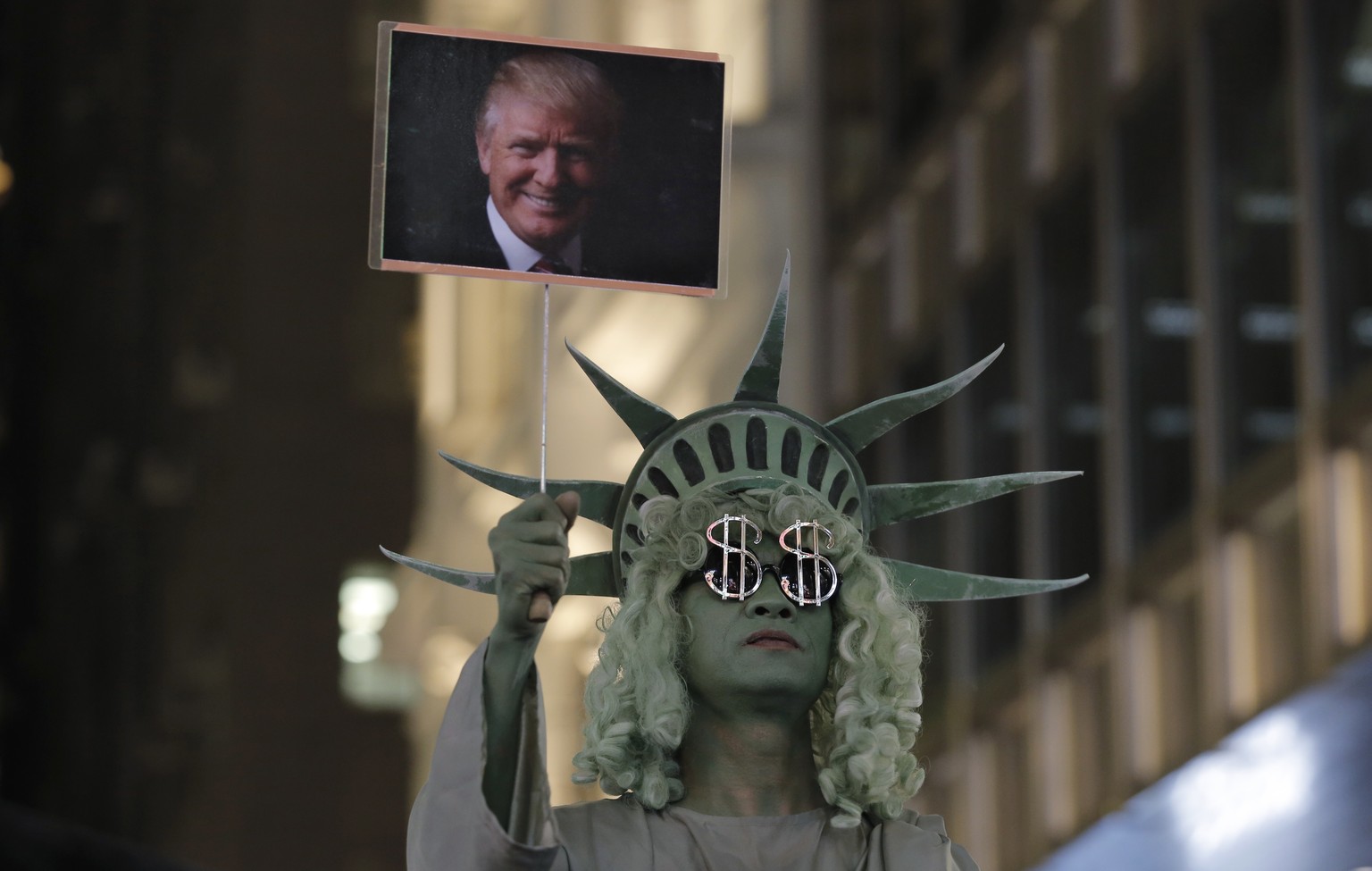 A street performer dressed as the Statue of Liberty holds up a picture of U.S. President-elect Donald Trump in Hong Kong&#039;s downtown, Wednesday, Nov. 9, 2016. Around the world, people reacted with ...