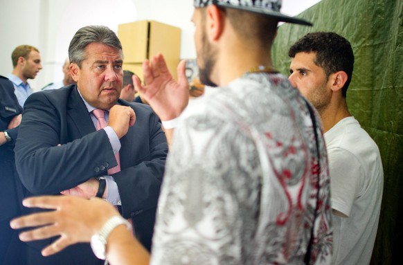 epa04890447 German Minister for Economic Affairs and Energy Sigmar Gabriel (L) talks to refugees during a visit to the Federal Police Station in Frankfurt am Main, Germany, 20 August 2015. EPA/CHRISTO ...
