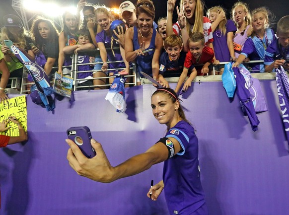 FILE - In this June 23, 2016, file photo, Alex Morgan, of the Orlando Pride, takes a selfie for a fan after the Pride beat the Houston Dash in a soccer match at Camping World Stadium in Orlando, Fla.  ...
