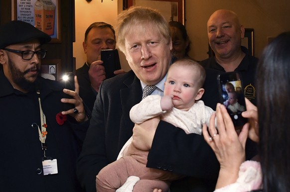 Britain&#039; Prime Minister Boris Johnson holds a baby as he meets with supporters at the Lych Gate Tavern in Wolverhampton, England, Monday, Nov. 11, 2019 as part of the General Election campaign tr ...