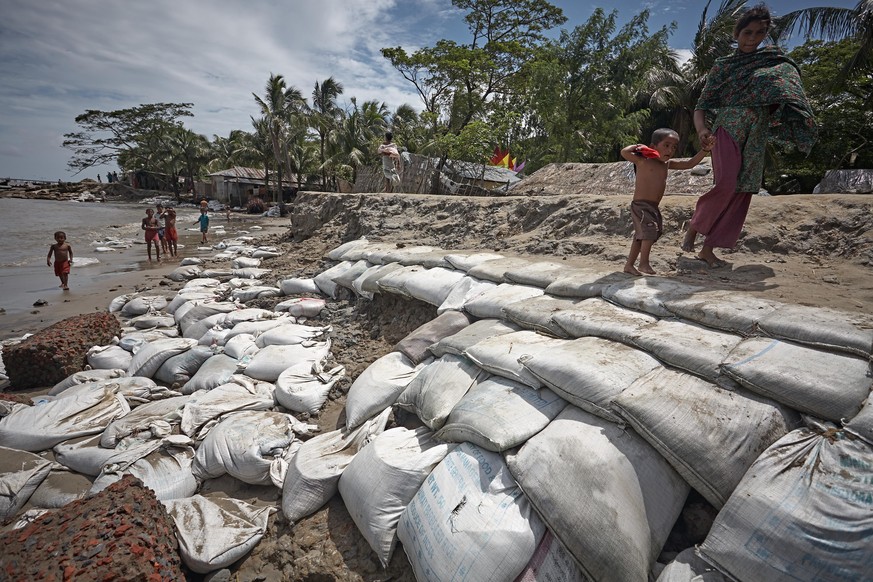In Kutubdia, an der Küste Bangladeschs, versucht man mit Sandsäcken die am Strand liegenden Häuser vor den steigenden Wasserpegeln zu schützen.