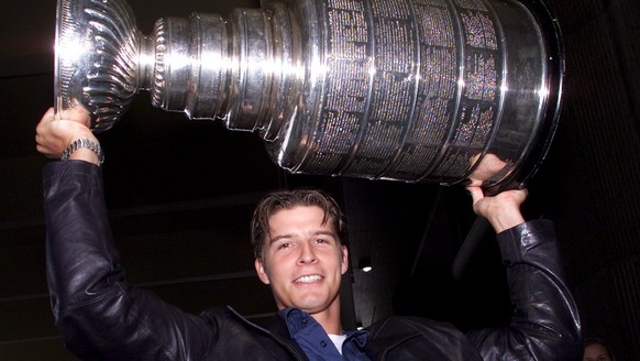 David Aebischer, Torhueter bei Colorado Avalanche, stemmt den aus Kanada in die Schweiz gebrachten, 16 Kilogramm schweren, silbernen Stanley Cup, am Freitag, 31. August 2001, auf dem Flughafen Zuerich ...