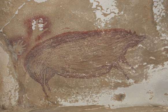 epa08936514 An undated handout photo made available byAustralia&#039;s Griffith University shows the painting of a wild pig and two hand prints dated at least 45,500 years, recently discovered at Lean ...